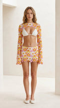 Front view of model wearing pink floral crochet shrug and mini skirt set
