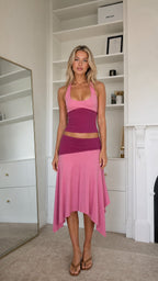 Model wearing pink two-piece halter top and asymmetrical midi skirt set from front