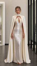 Front view of model wearing champagne sequin evening dress with attached cape