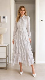 Front view of model wearing white polka dot midi dress with tie neck