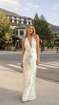 Front view of woman wearing white sequin halter maxi dress outdoors
