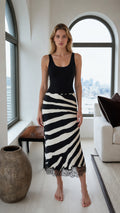 Front view of a black and white zebra print lace hem midi skirt styled with a black tank top