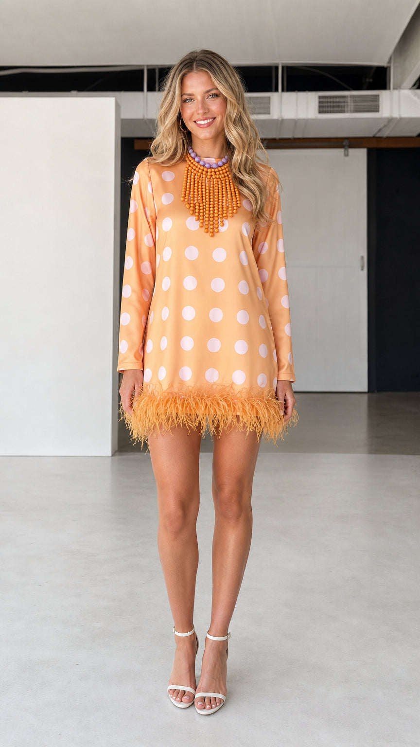 Front view of model wearing orange polka dot feather hem dress
