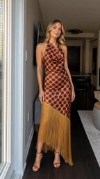Front view of woman wearing brown polka dot halter maxi dress with fringe hem