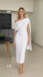 Front view of woman wearing white one-shoulder midi dress with cape detail