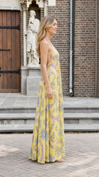 Model wearing yellow floral halter maxi dress from the side
