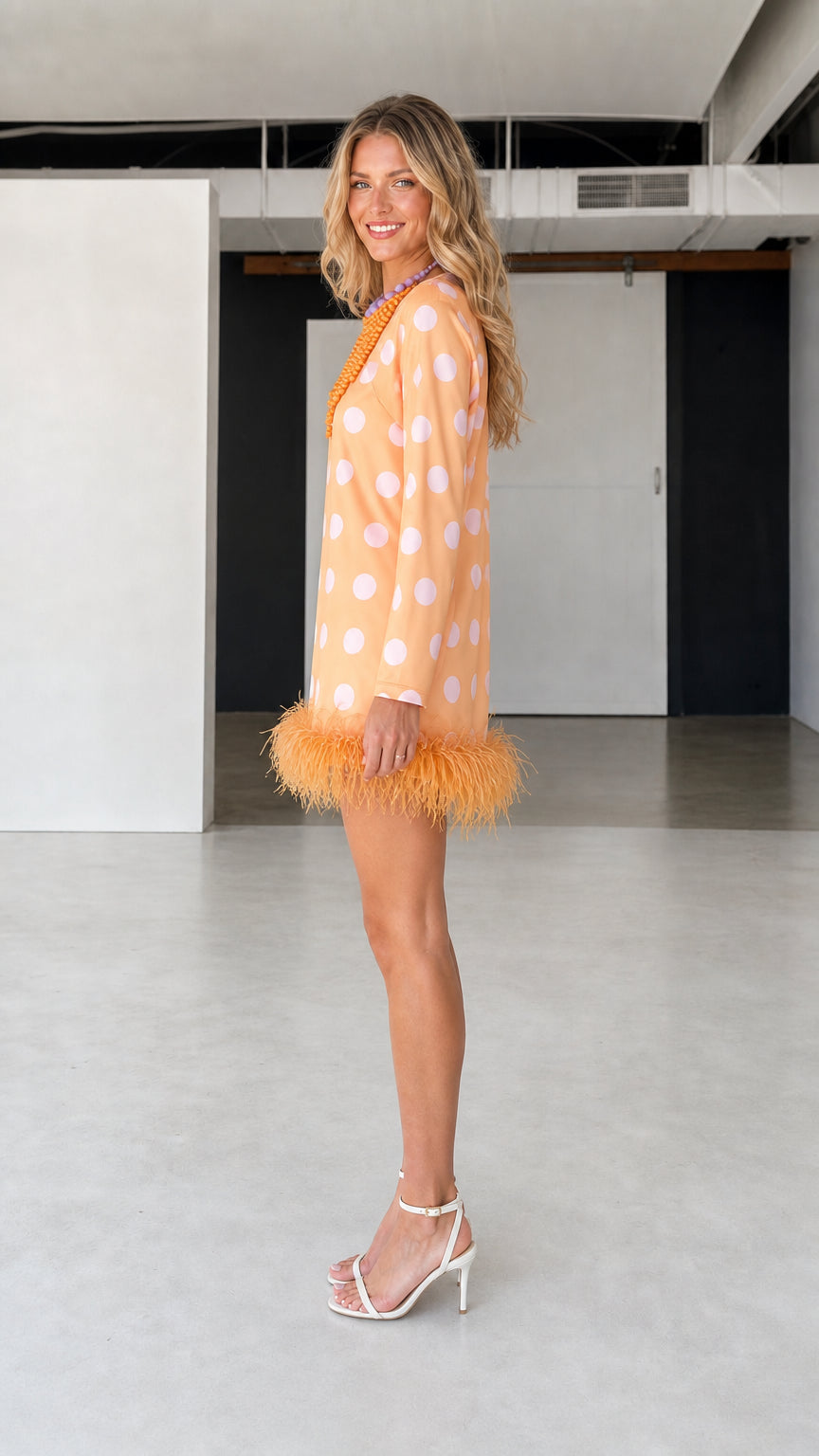 Side profile of model in orange polka dot feather hem dress