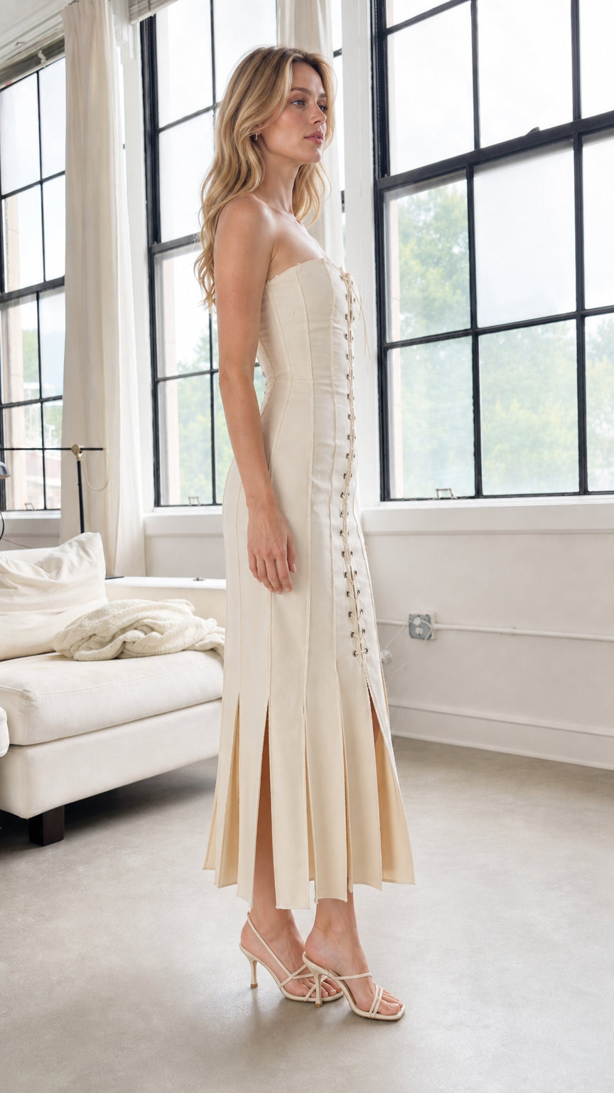 Side profile of model in beige strapless midi dress