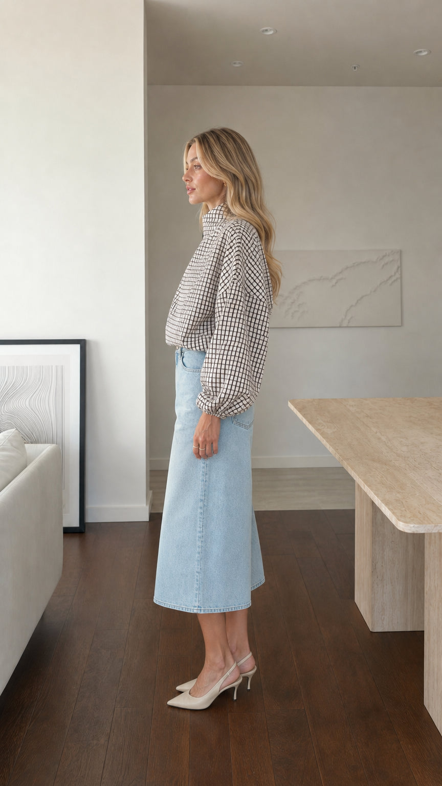 Side profile of model wearing white plaid high-neck blouse