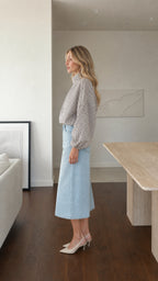 Side profile of model wearing white plaid high-neck blouse