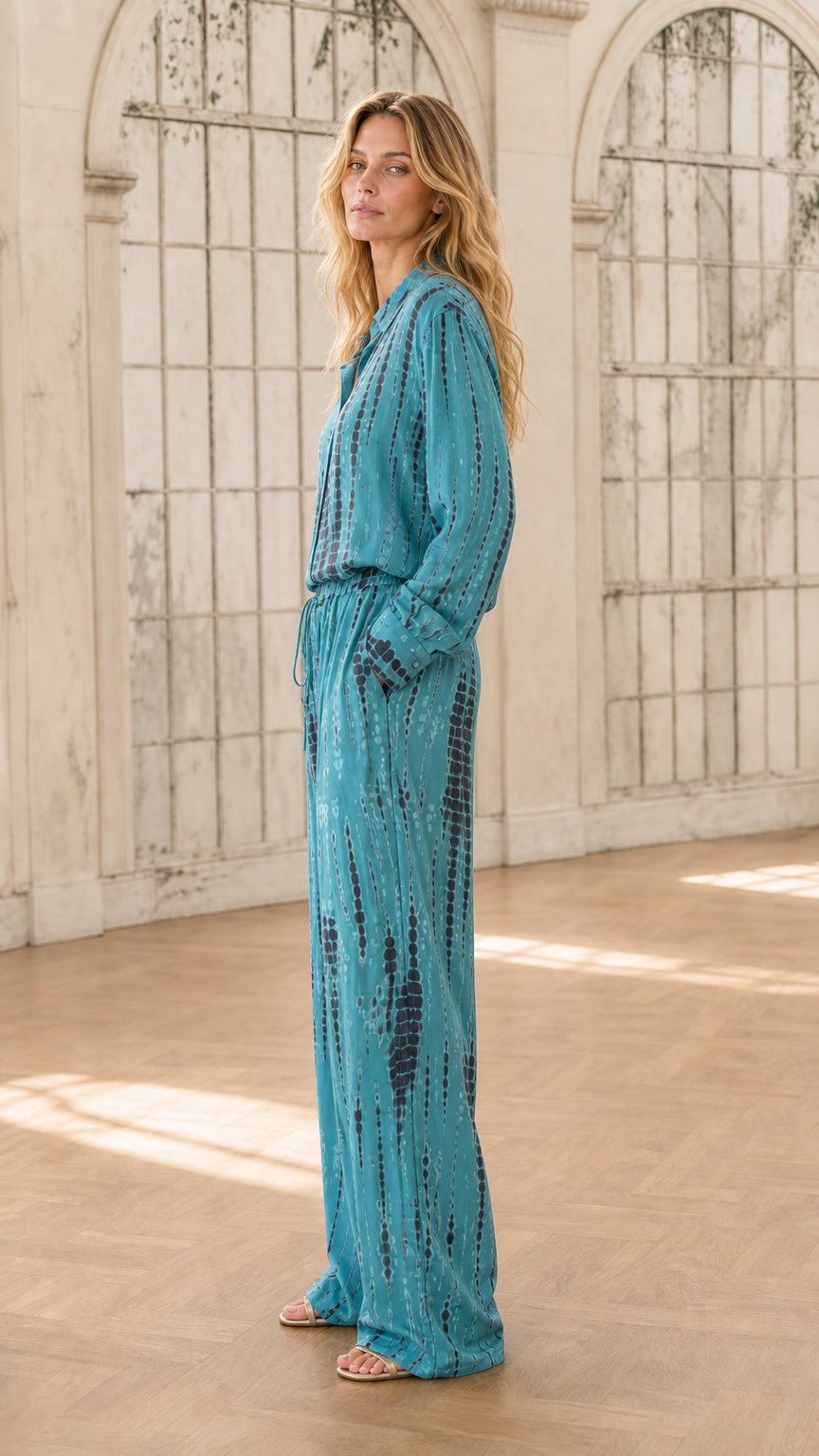Side profile of model in teal tie-dye jumpsuit