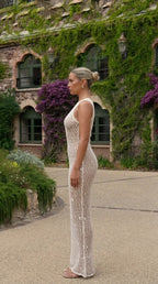 Side profile of woman in beige crochet maxi dress