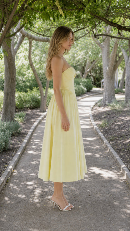 Side profile view of yellow strapless corset midi dress