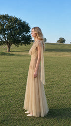 Side profile of model wearing champagne tulle maxi dress