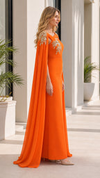 Side profile view of orange evening dress with flowing cape