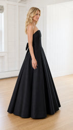 Side profile view of model in black strapless evening gown