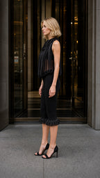 Side profile of model wearing black pleated fringe two-piece set