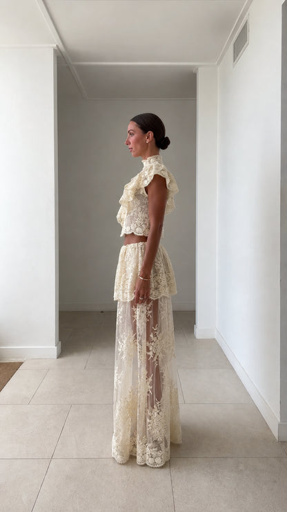 Side profile of model in ivory lace crop top and maxi skirt