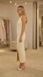 Side profile of woman in cream midi dress with front slit