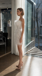 Model wearing white strapless feather mini dress side profile