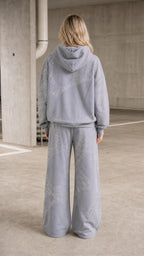 Back view of model showing back of grey rhinestone hoodie and pants