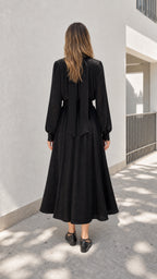 Model wearing black midi dress showing back bow detail