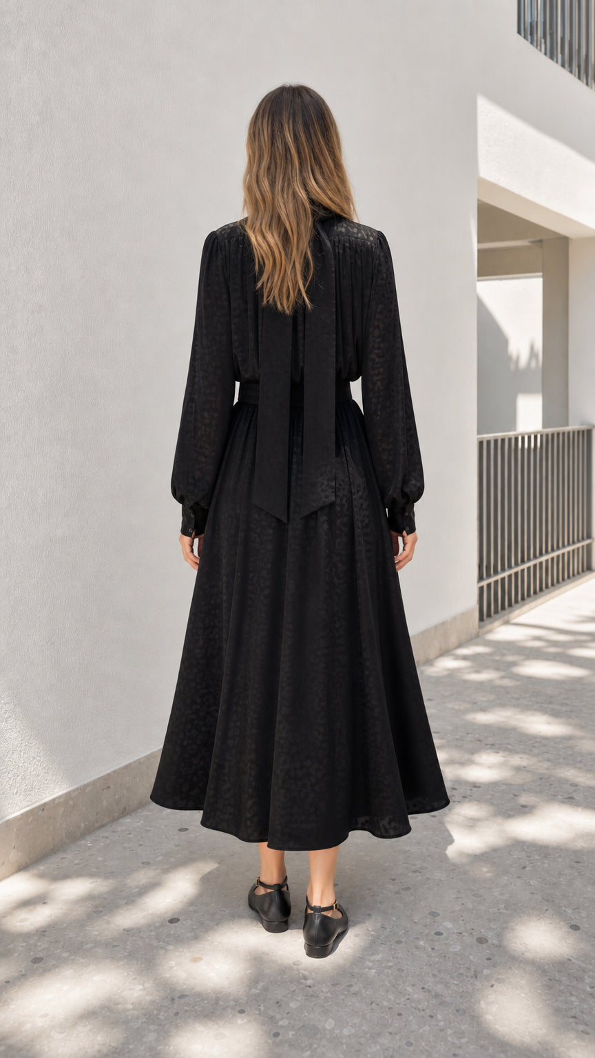 Model wearing black midi dress showing back bow detail
