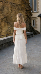 Back view of woman wearing ivory off-shoulder top and matching skirt