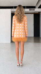 Back view of model in orange polka dot feather hem dress