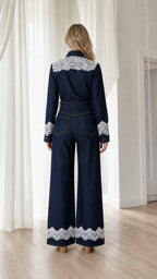 Back view showcasing white lace hem on dark denim jumpsuit