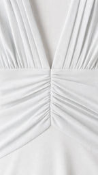 Close-up detail of pleated V-neck and ruched waist on white dress
