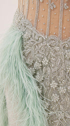 Close-up detail of crystal beading and feather trim on gown