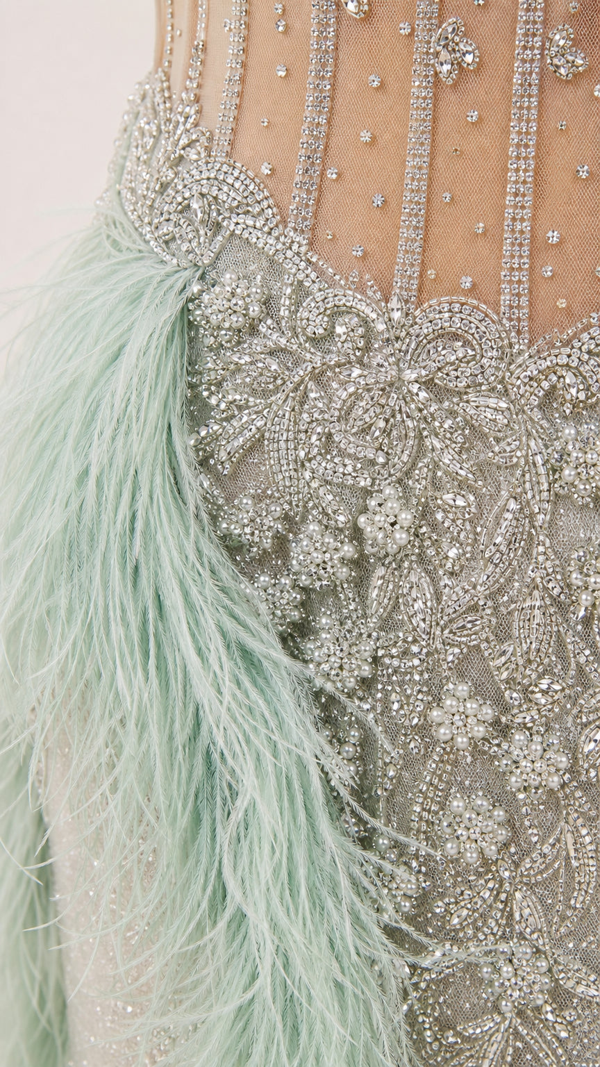 Close-up detail of crystal beading and feather trim on gown