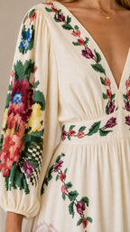 Close-up detail of embroidery on cream dress bodice and sleeve