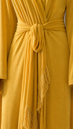 Close-up detail of the waist tie and fringe trim on yellow dress