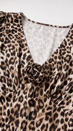 Close-up detail of V-neckline and rosette accent on leopard print fabric