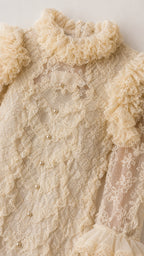Close-up of stand collar and pearl buttons on cream lace dress