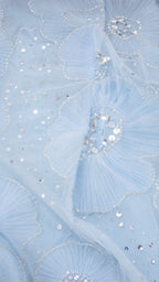 Close-up of light blue mesh fabric with sequin floral embroidery