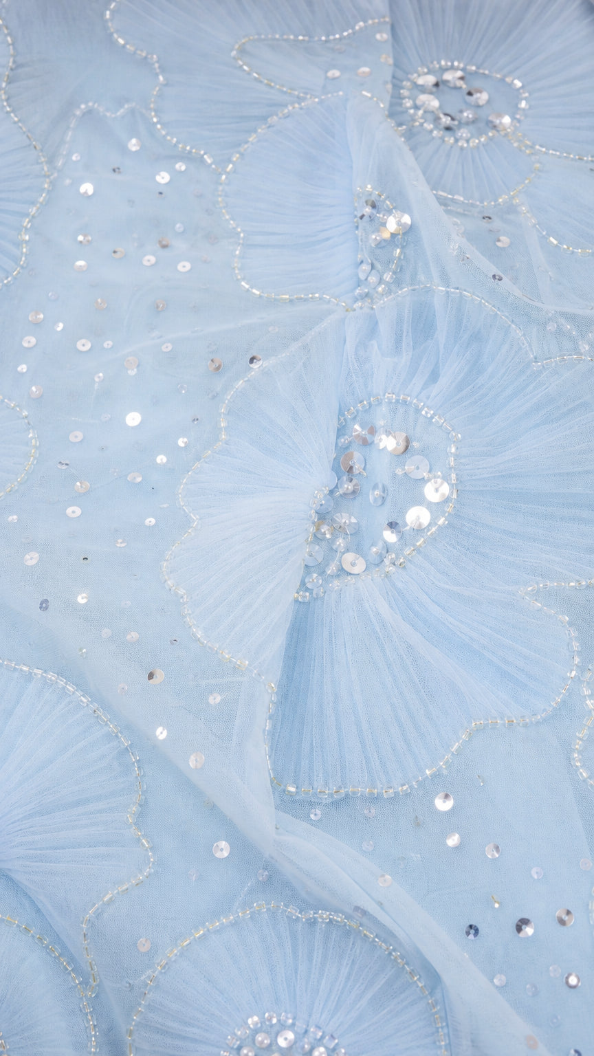 Close-up of light blue mesh fabric with sequin floral embroidery