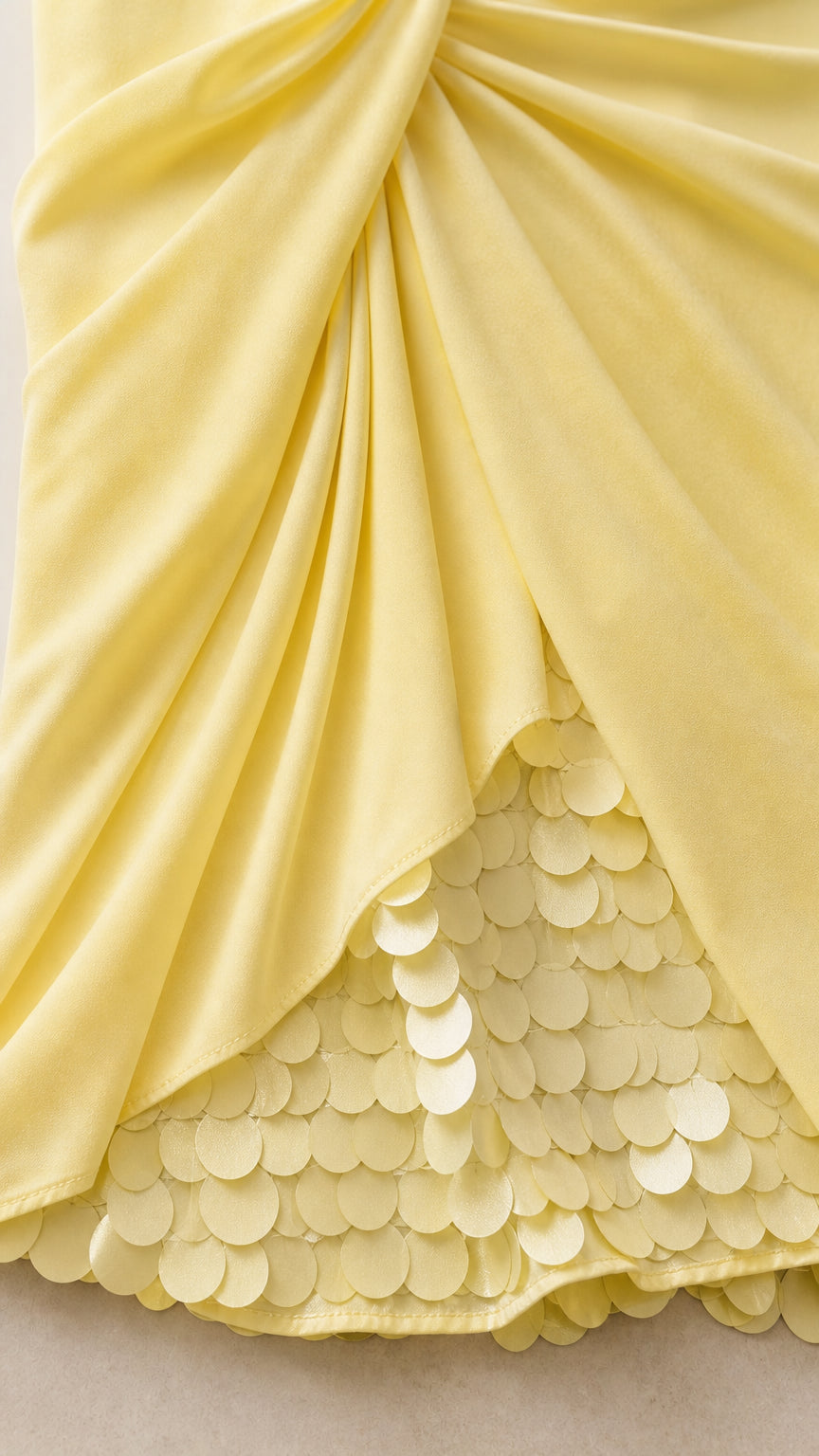 Close up detail of yellow draped fabric and circular sequin hem