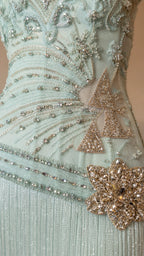 Close-up detail of embroidery and floral appliqué on mint dress
