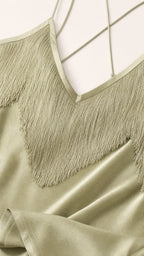 Close-up detail of V-neckline, fringe trim, and delicate straps