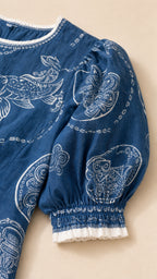 Close-up detail of blue dress sleeve and embroidered pattern
