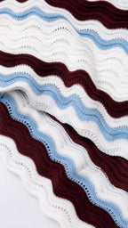Close-up of wavy striped knit fabric in burgundy, blue, and white