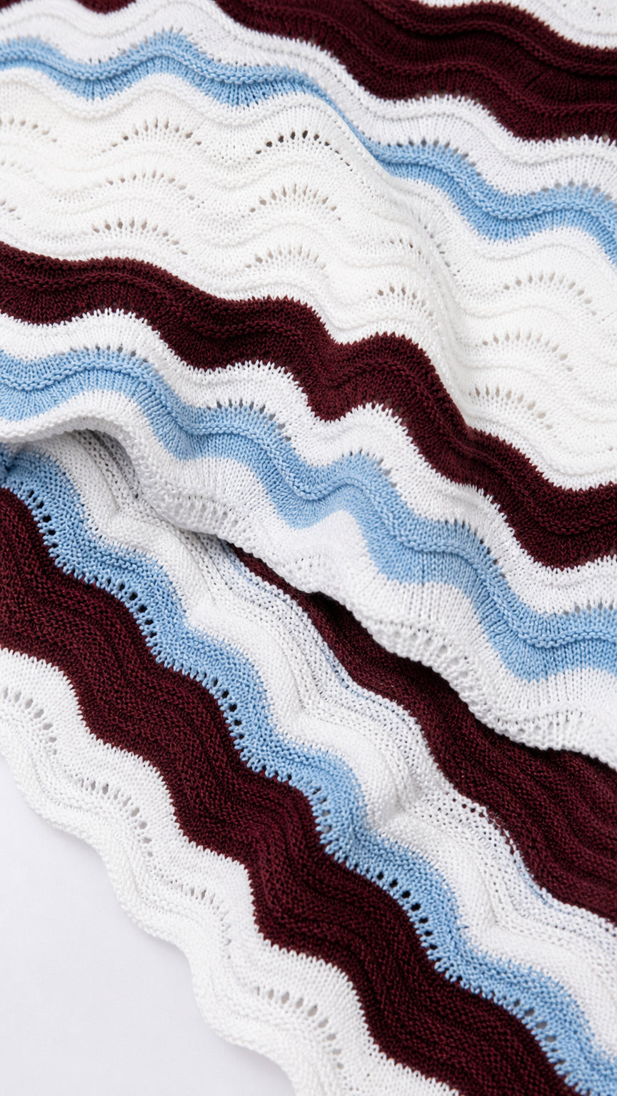Close-up of wavy striped knit fabric in burgundy, blue, and white