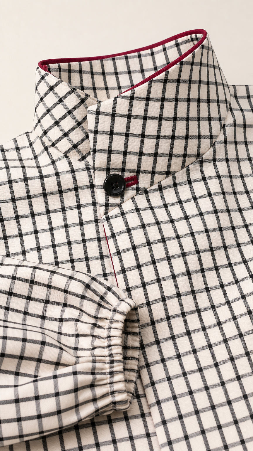 Close-up detail of high collar, contrast trim, and button on plaid blouse
