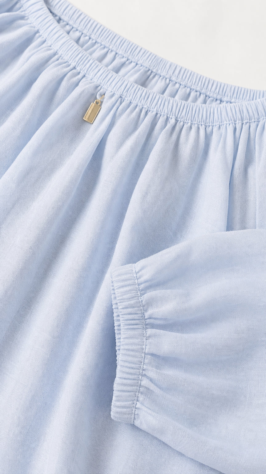 Close-up detail of gathered neckline and sleeve cuff on light blue set
