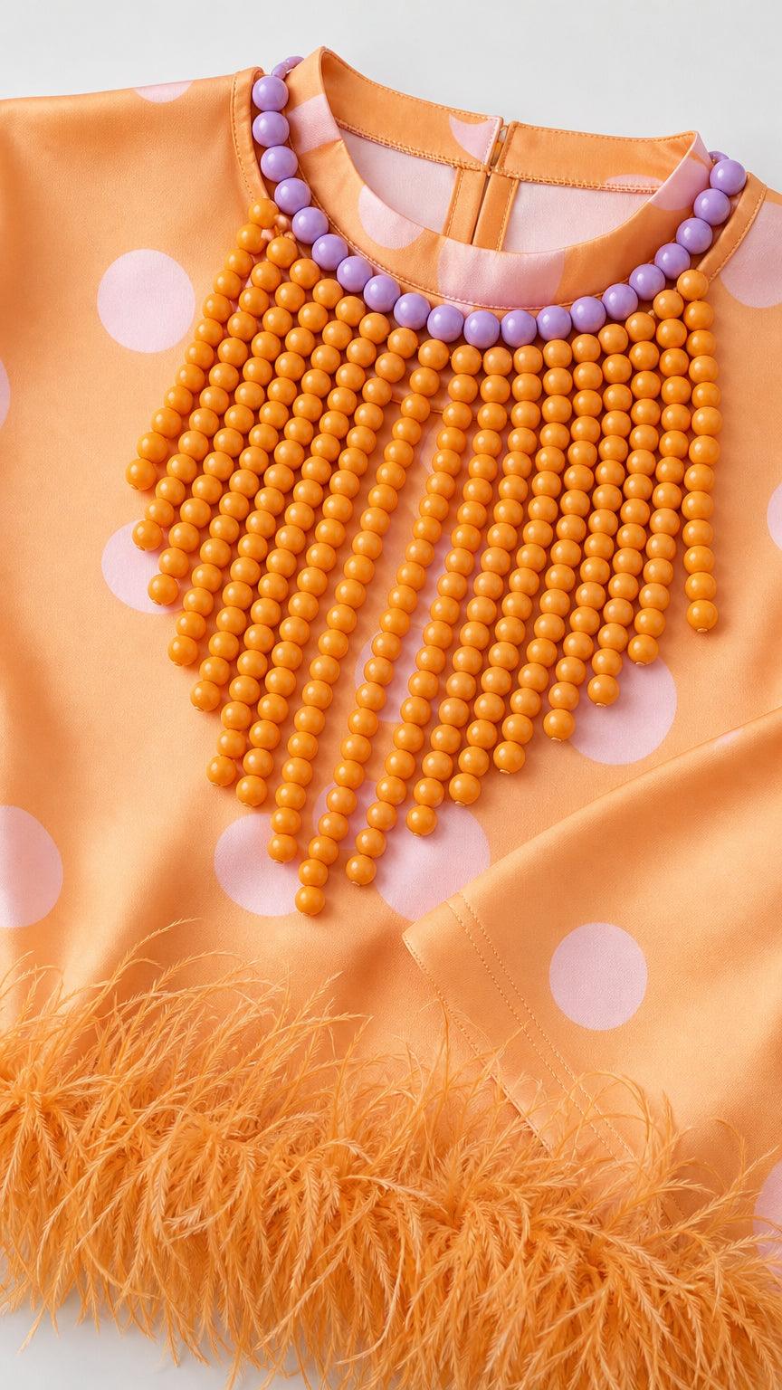 Close-up of orange dress fabric and feather hem detail
