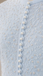 Close-up of textured knit fabric and pearl buttons on light blue dress