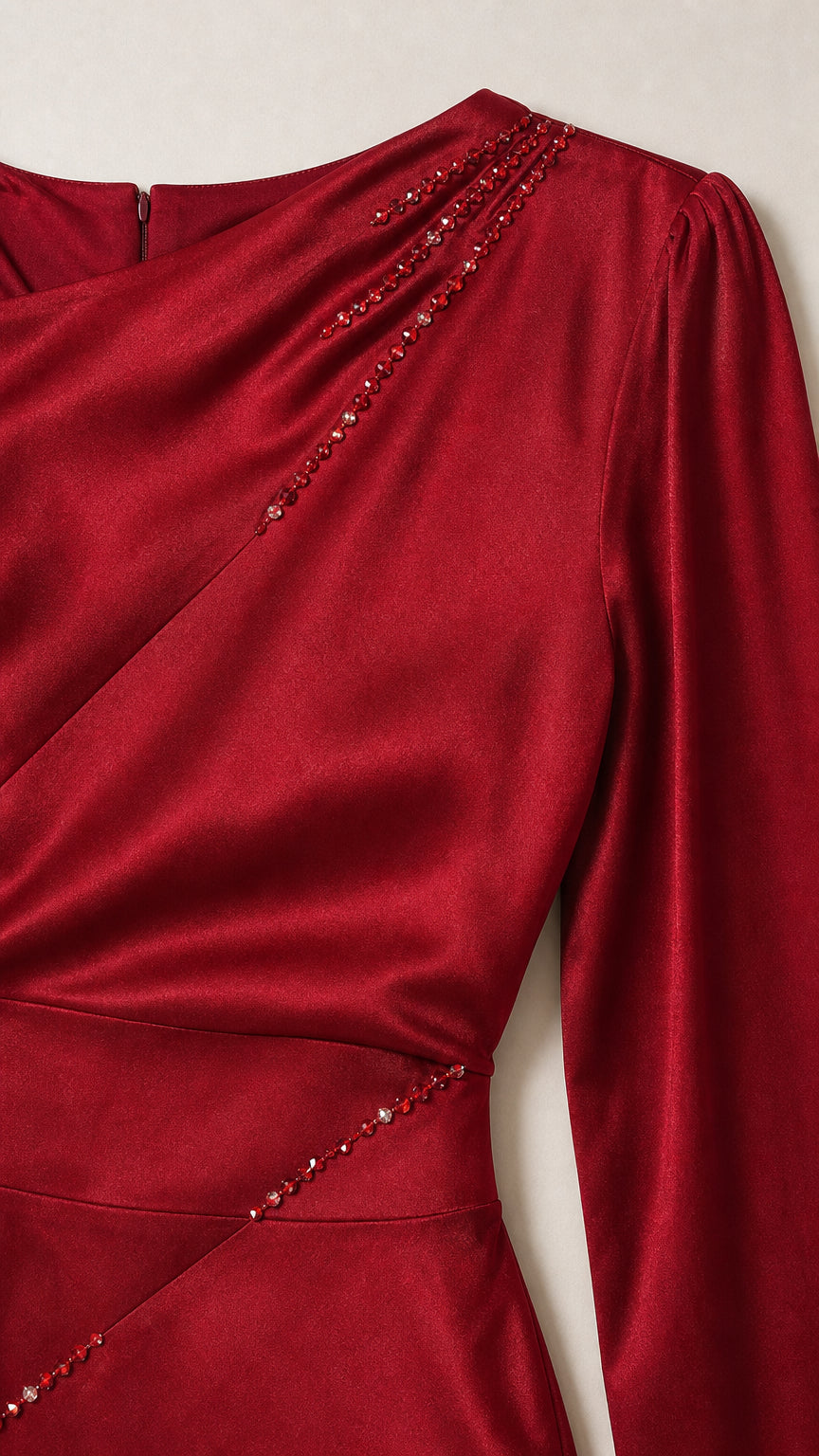 Close-up detail of beaded embellishment and satin fabric on red gown